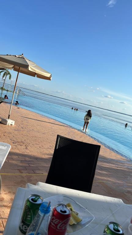 a person standing on the beach near the ocean at Apartamento no tropical executive hotel com varanda, 1 cama de casal e 2 camas de solteiro in Manaus