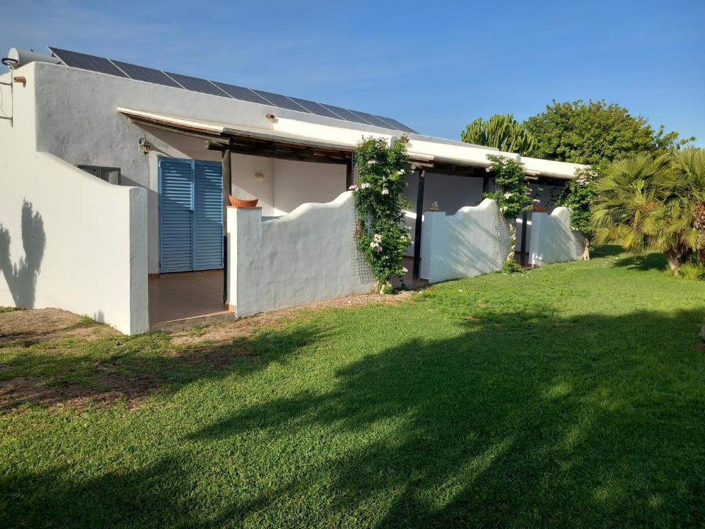 une maison blanche avec une pelouse verte devant elle dans l'établissement Apartamentos Cala Isabel, à Zahora