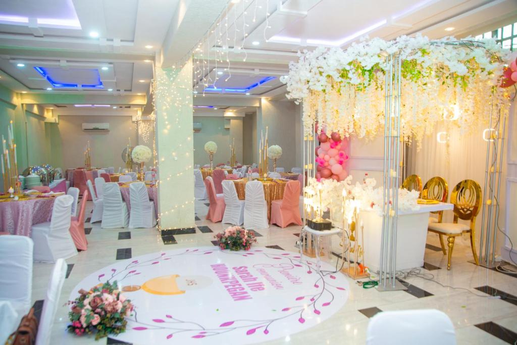 un salón de banquetes con mesas y sillas blancas y rosas en HOTEL MAVILLA Cotonou en Cotonú