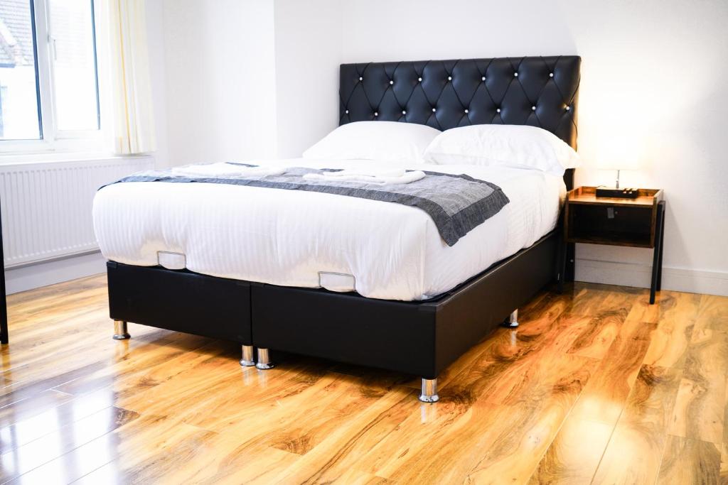 uma cama com uma moldura preta e lençóis e almofadas brancos em Centra Studios em Londres