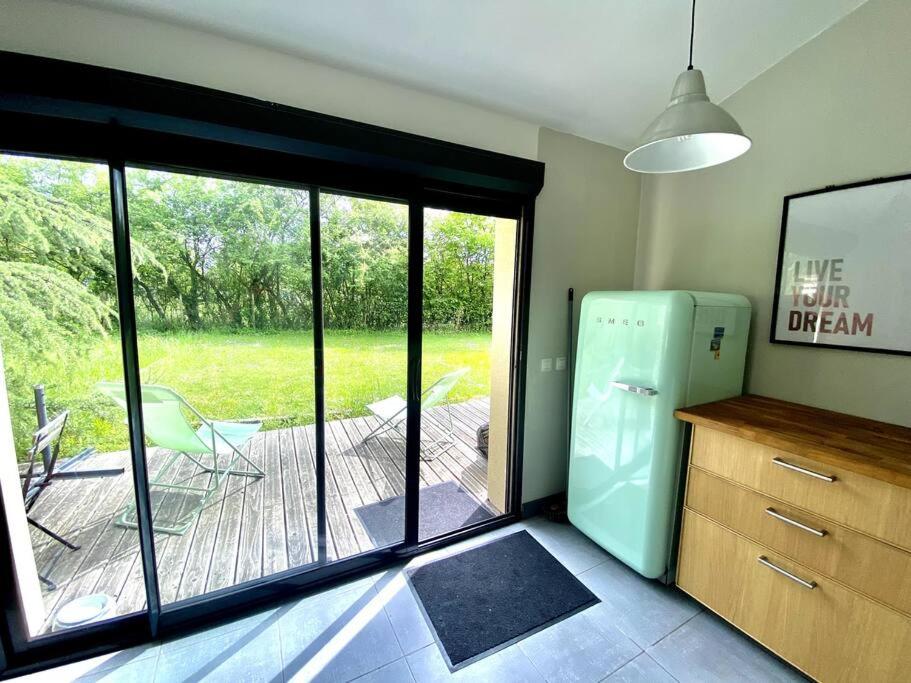 une cuisine avec un réfrigérateur et un patio avec une terrasse dans l'établissement La Lande - Petite maison avec jardin, à Vendat