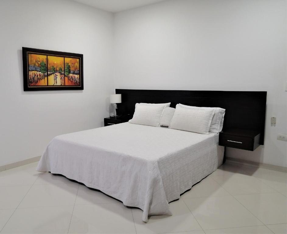 a bedroom with a white bed with a black headboard at Hotel Panorama in Sincelejo