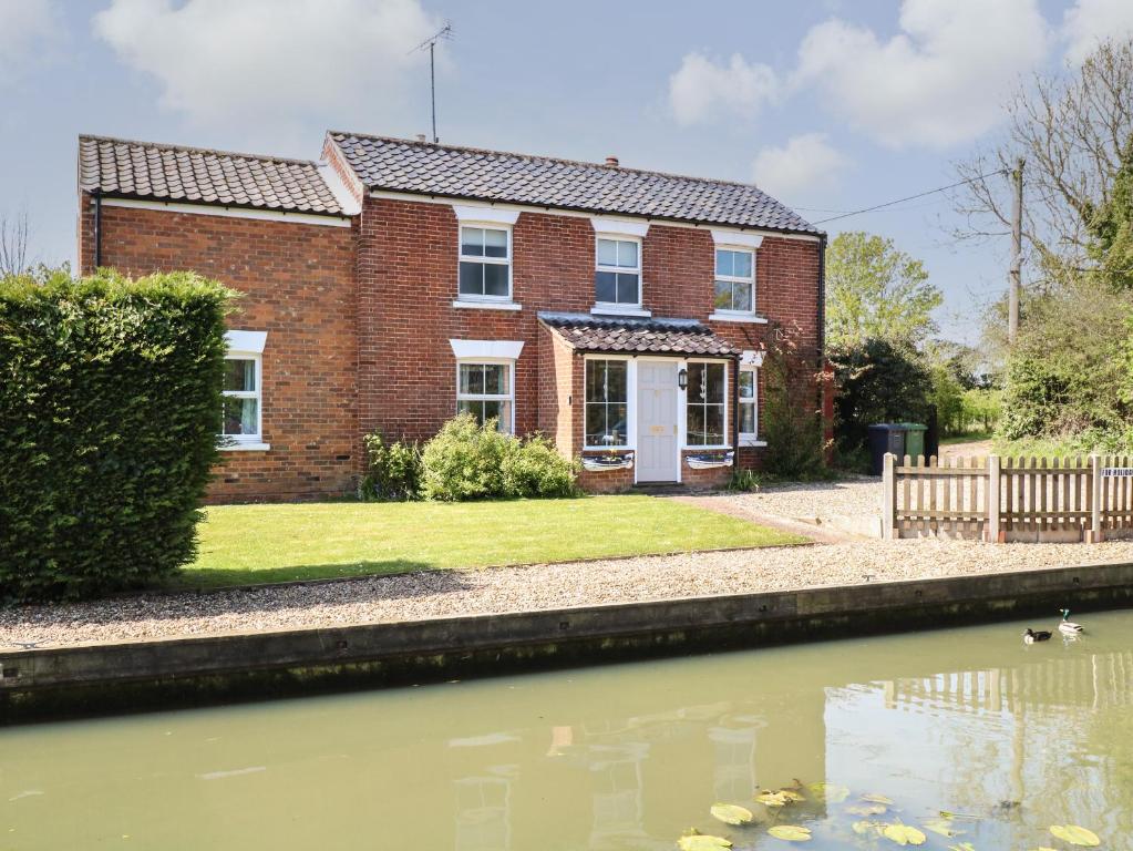 a brick house with a pond in front of it at Riverside Cottage in Norwich