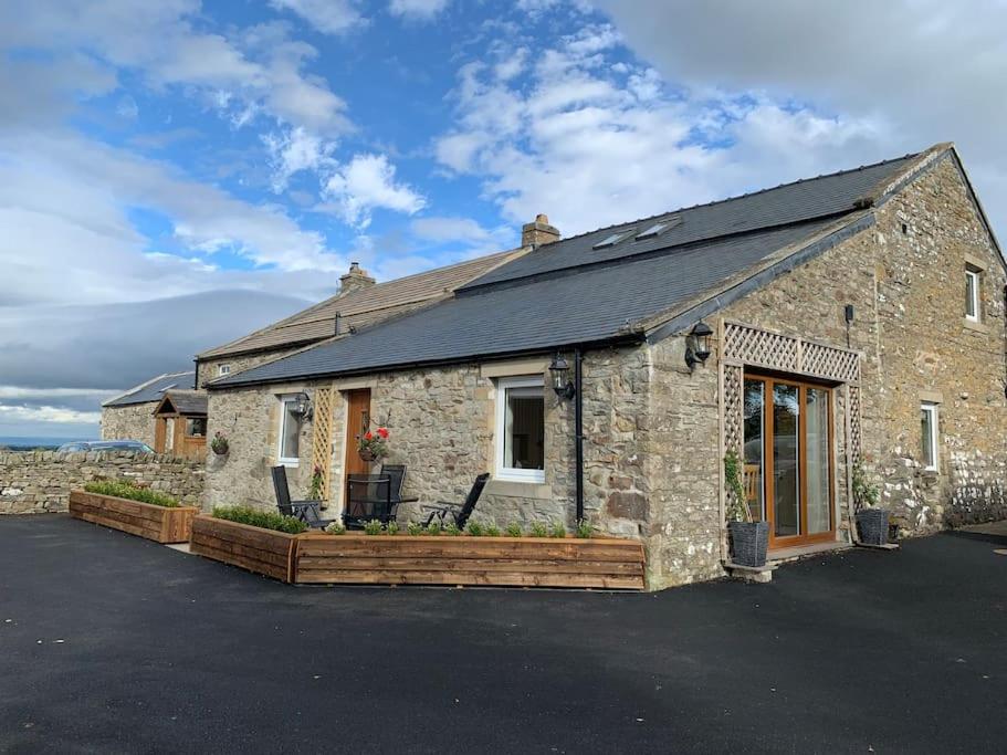 um edifício de pedra com um alpendre em The Byre @ Cow Close - Stay, Rest and Play in the Dales. em Leyburn