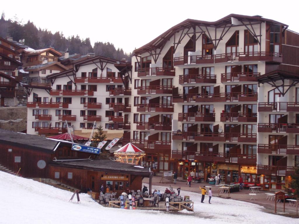 un gran edificio con gente parada fuera en la nieve en Ski-in ski-out 1 bed, La Tania, en Courchevel