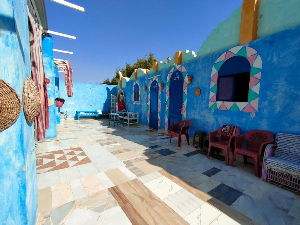 Zimmer mit einer blauen Wand mit Stühlen und Tischen in der Unterkunft Kamel House in Assuan