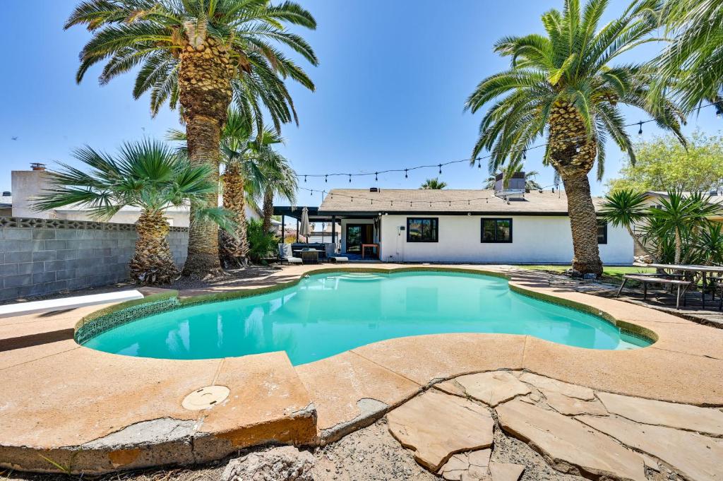 a swimming pool with palm trees in front of a house at Yuma Vacation Rental with Private Pool and Patio! in Yuma