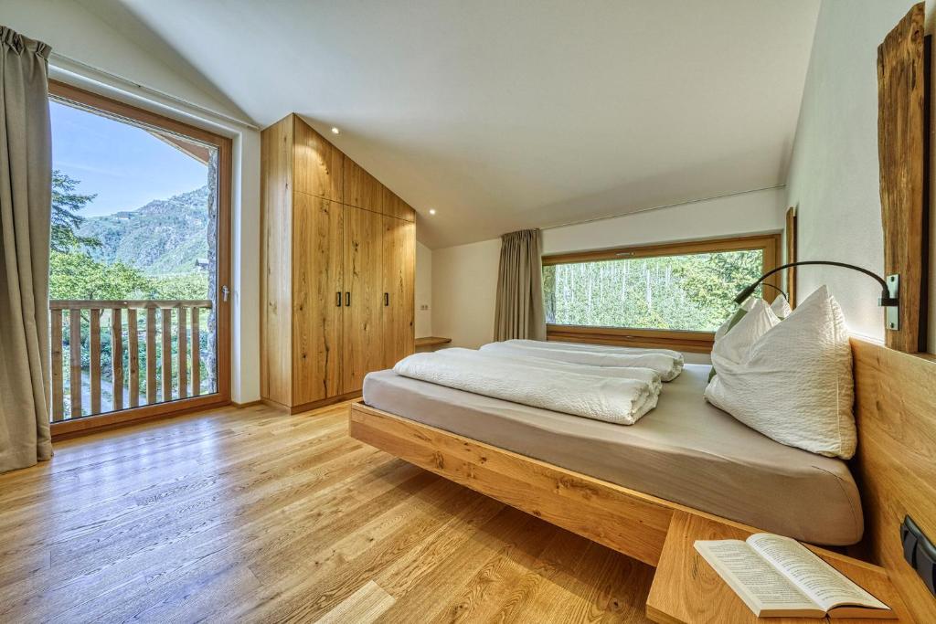 sypialnia z dużym łóżkiem i dużym oknem w obiekcie Pröfinghof - Urlaub auf dem Biobauernhof w mieście Parcines