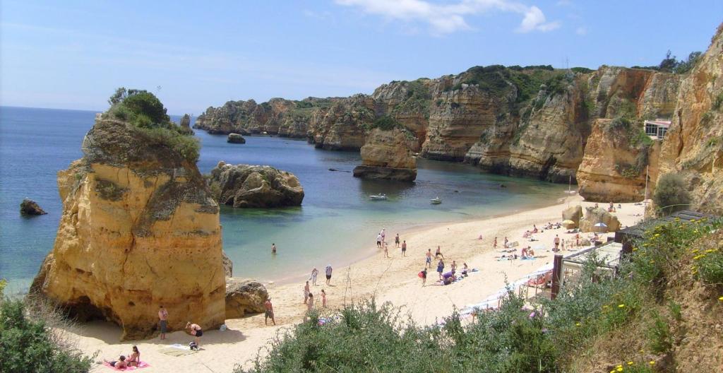 un grupo de personas en una playa cerca del océano en Casinha das Papoilas en Lagos