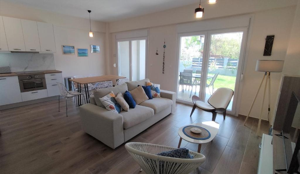 a living room with a couch and a table and a kitchen at To Helidoni Apartment & Gardens in Nikiti