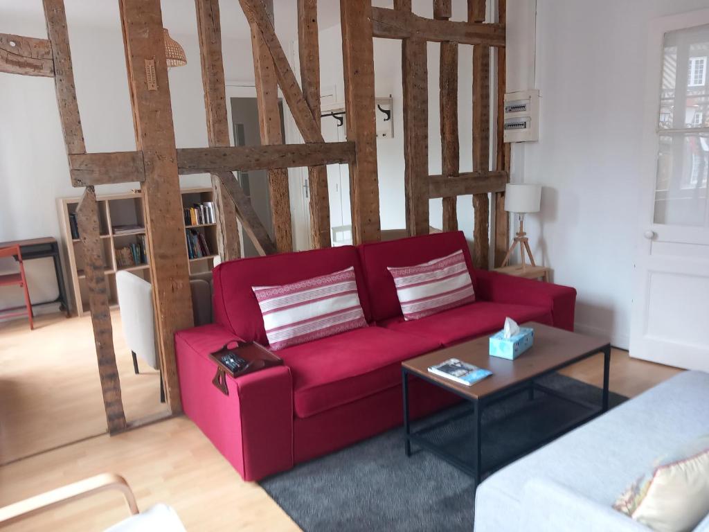 uma sala de estar com um sofá vermelho e uma mesa em Le Léon em Honfleur