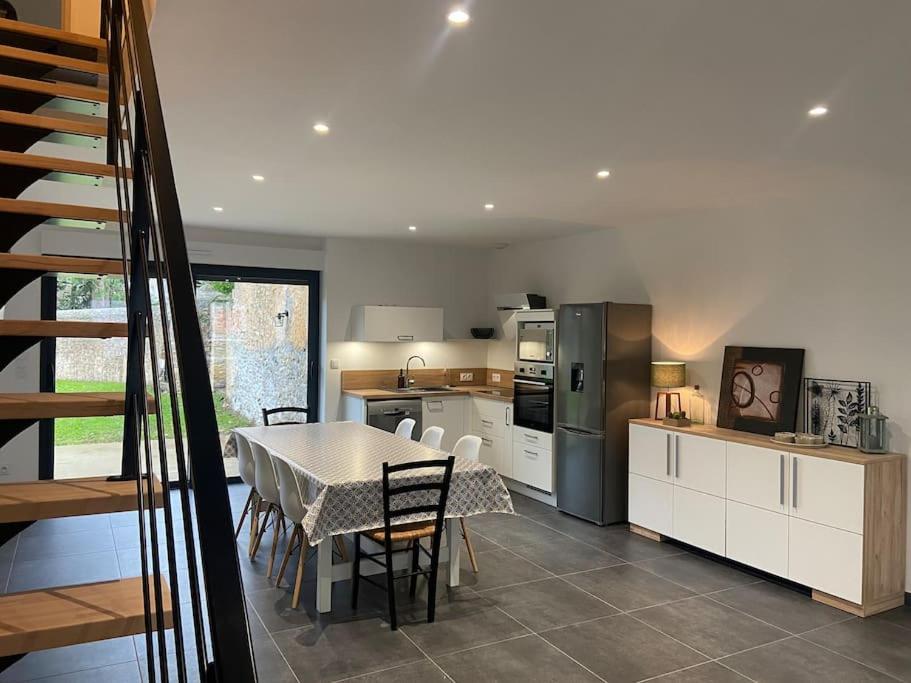 a kitchen with a table with chairs and a kitchen with a refrigerator at Les prunelles maison de village de 4 à 8 personnes in Précigné