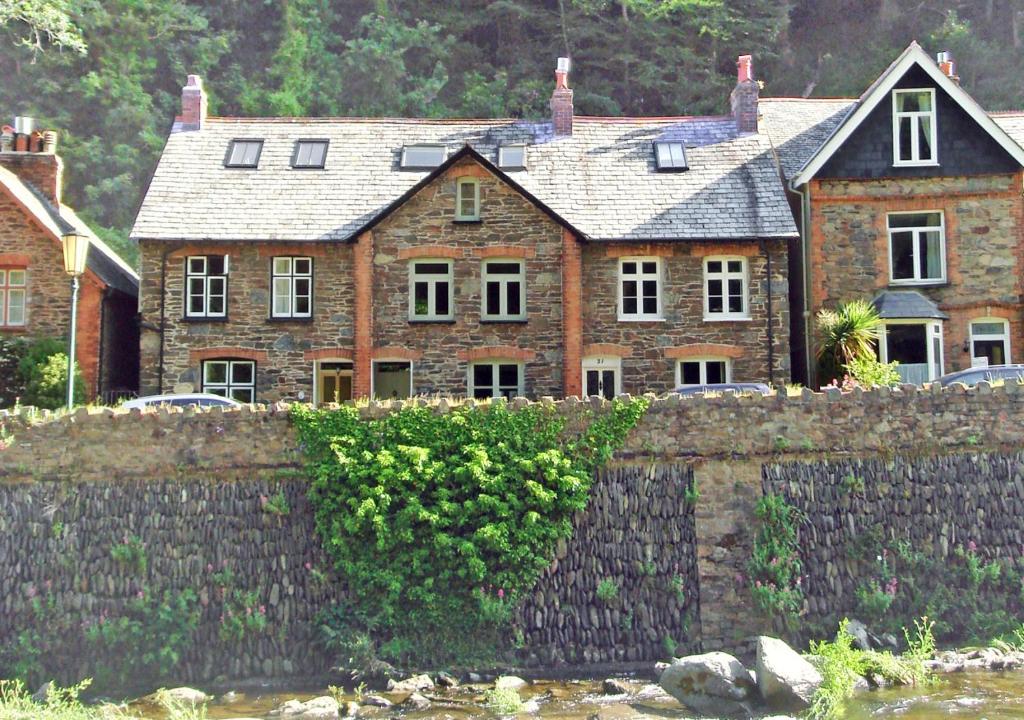 een groot bakstenen huis achter een stenen muur bij River Cottage in Lynmouth