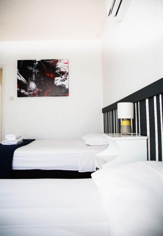 a white room with two beds and a lamp at Olive Island in Larnaka