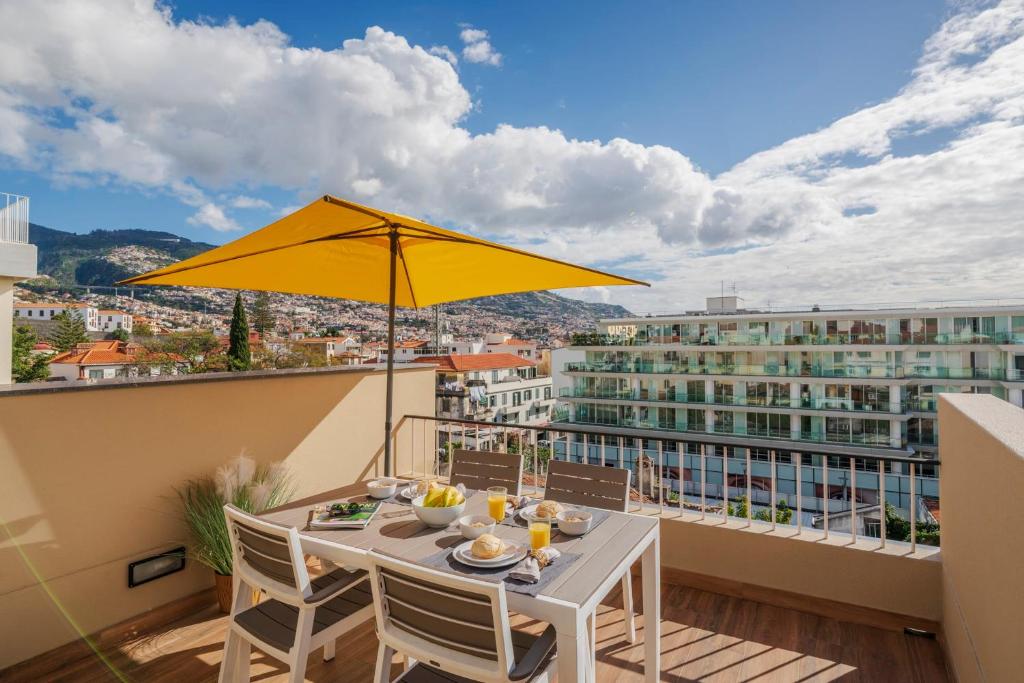 a table with a yellow umbrella on a balcony at Alegria Flat by An Island Apart in Funchal