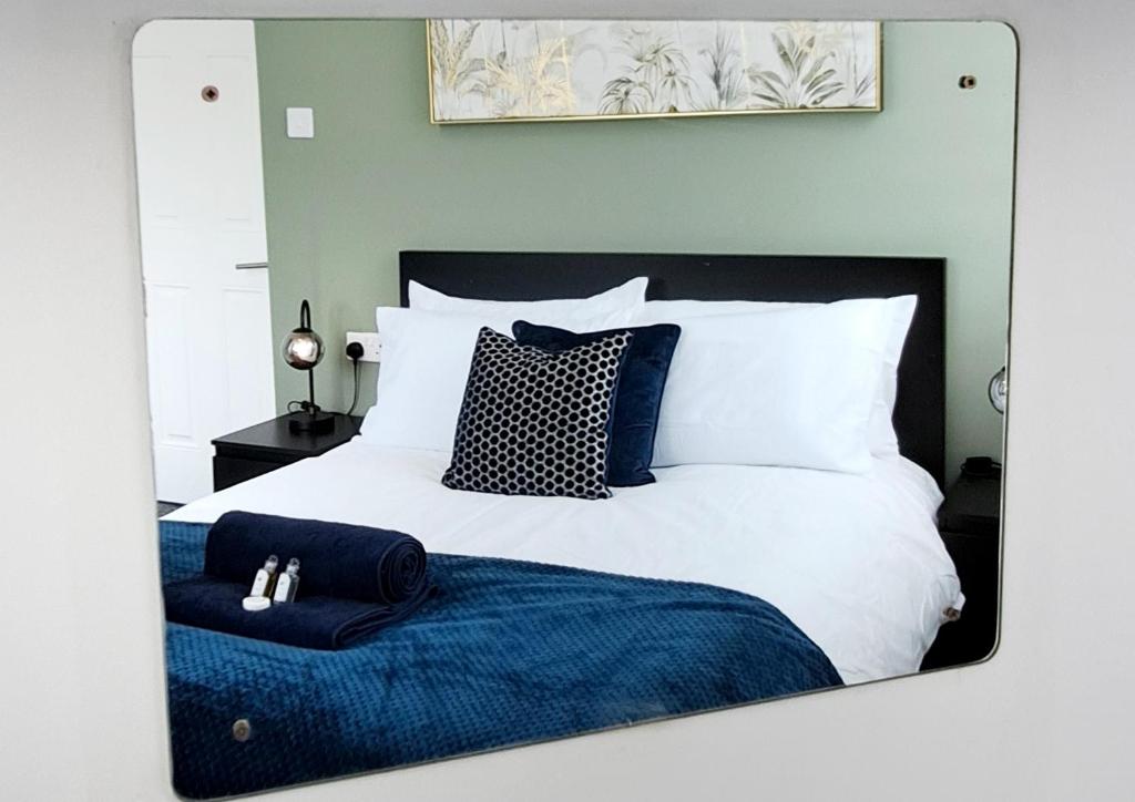 espejo reflejo de una cama con manta azul en Bright 3 Bed Apartment With Terrace, Free Parking!, en Watford