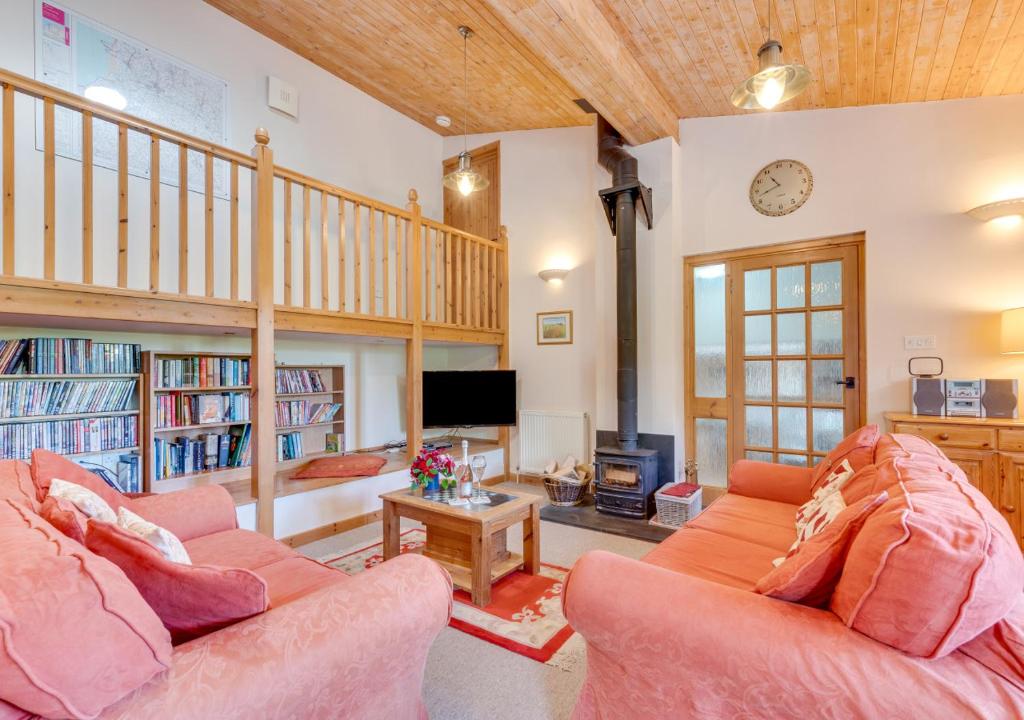 sala de estar con 2 sofás rosados y TV en Swallow Barton en Atherington