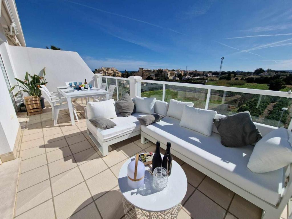 eine Terrasse mit einem Sofa und einem Tisch auf dem Balkon in der Unterkunft V19 Ático con impresionantes vistas al mar B16 in Denia