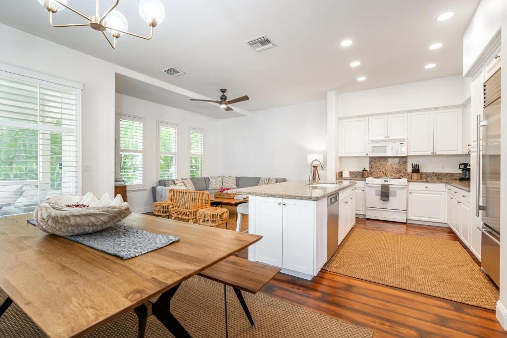 a kitchen with white cabinets and a wooden table at Sunset Villa - Walk To Koolina Beaches - Sleeps 8 in Kapolei