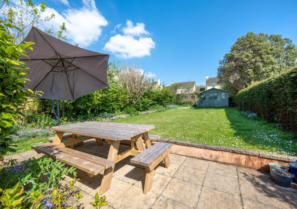 a wooden picnic table with an umbrella and benches at Sunnymead in Barnstaple