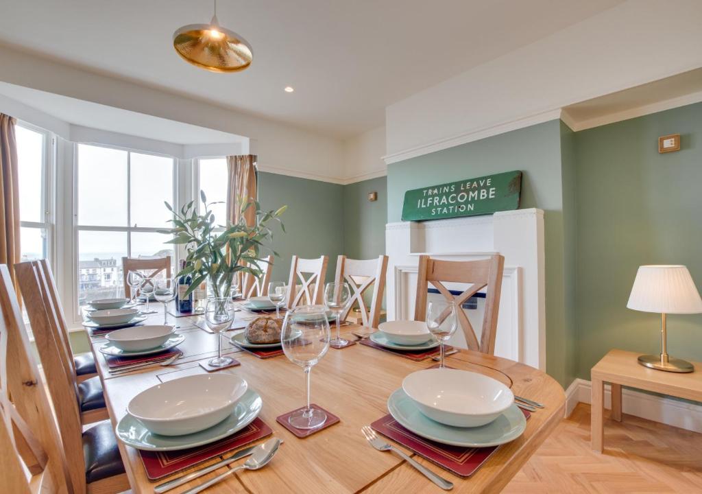 a dining room with a table with plates and glasses at St Agnes Sleeps 6 in Ilfracombe