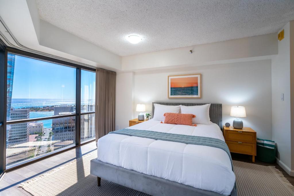 a bedroom with a large bed and a large window at Stunning Skyview, Pool, Fabulous Location! in Honolulu