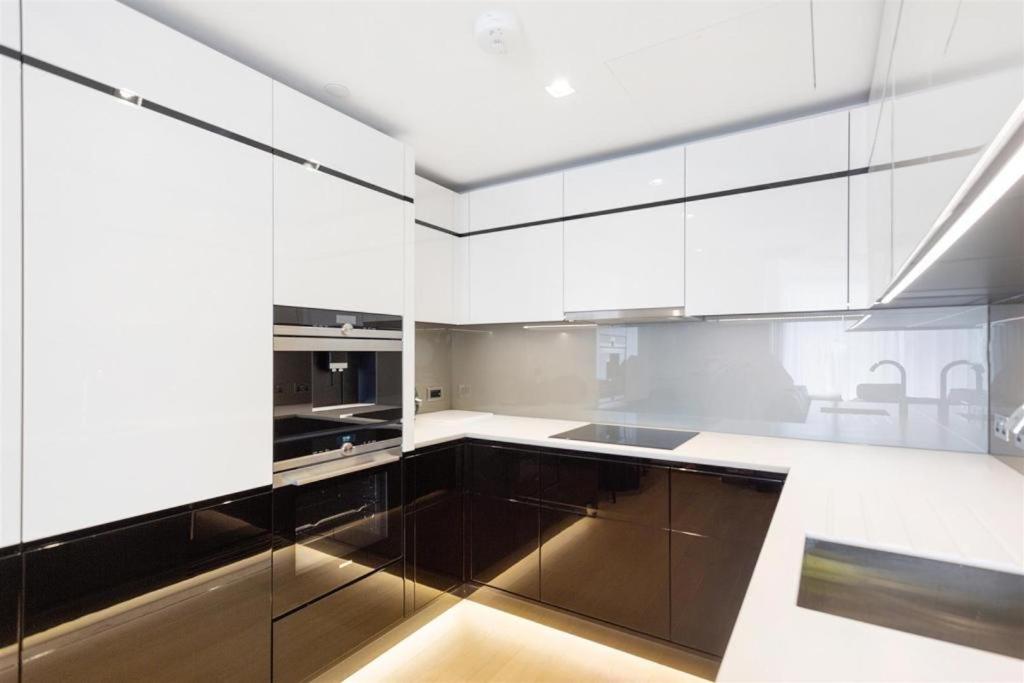 a kitchen with white cabinets and stainless steel appliances at New River Plaza Apartment in London