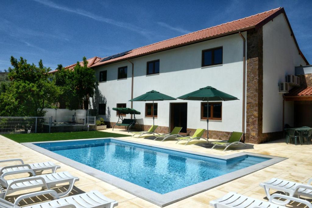 una piscina con sillas y sombrillas frente a una casa en Spacious Villa in Celorico de Basto with Private Pool, en Celorico de Basto
