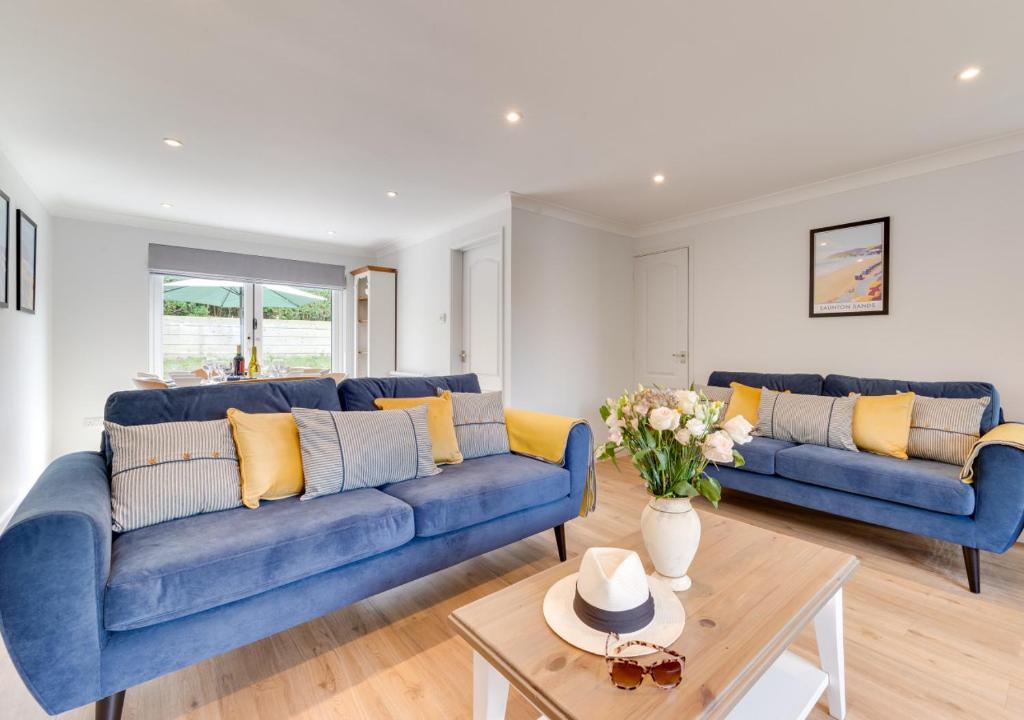 a living room with two blue couches and a table at Withyside in Croyde