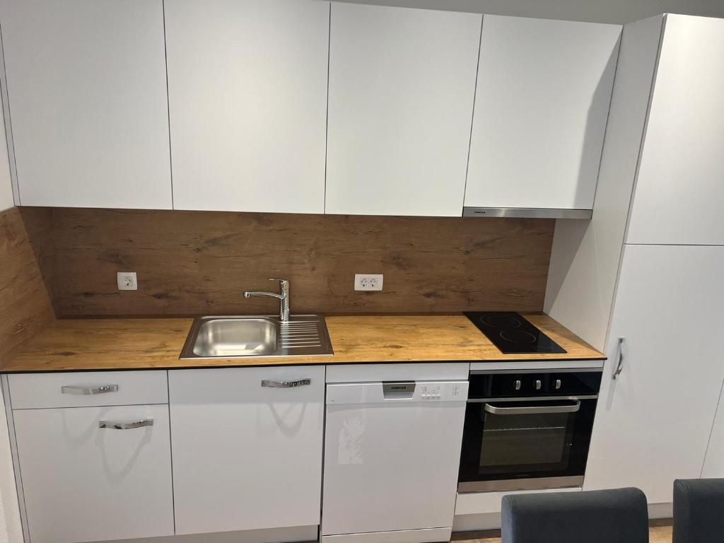 a small kitchen with white cabinets and a sink at Apartman Juric in Posušje