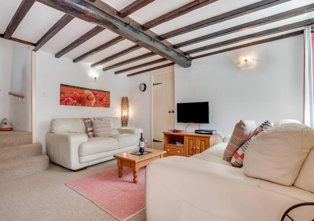 a living room with two white couches and a tv at Willow Cottage in Braunton