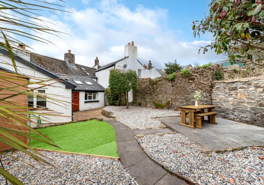 un jardín frente a una casa con una mesa de madera en Wisteria Cottage en Great Torrington