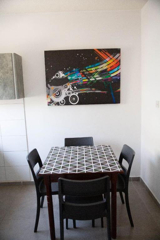 a dining room table with chairs and a painting on the wall at Olive Island in Larnaka