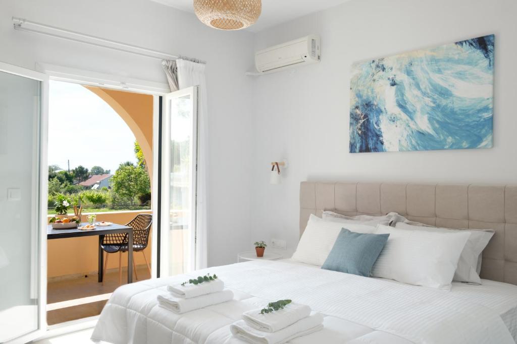 a white bedroom with a large bed and a table at Casa Campos Arillas in Arillas