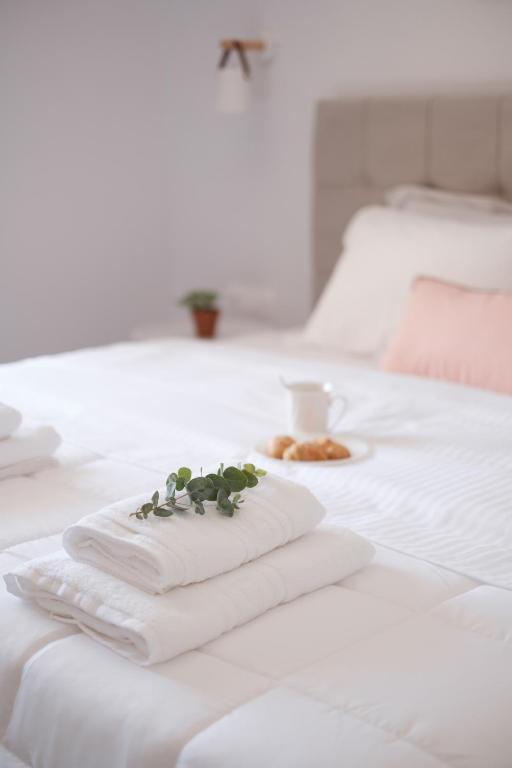 a stack of towels on a bed with a cup of coffee at Casa Campos Arillas in Arillas