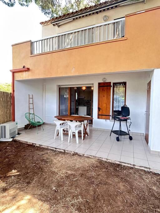un patio avec une table et des chaises devant une maison dans l'établissement La Pineda appt RDJ cosy à 200m du village natu, au Cap d'Agde