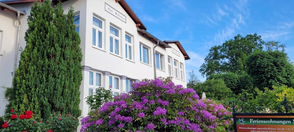 un edificio blanco con flores púrpuras delante de él en Ferienwohnungen Stranddistel - Apartments von 30 bis 75 qm, en Zinnowitz