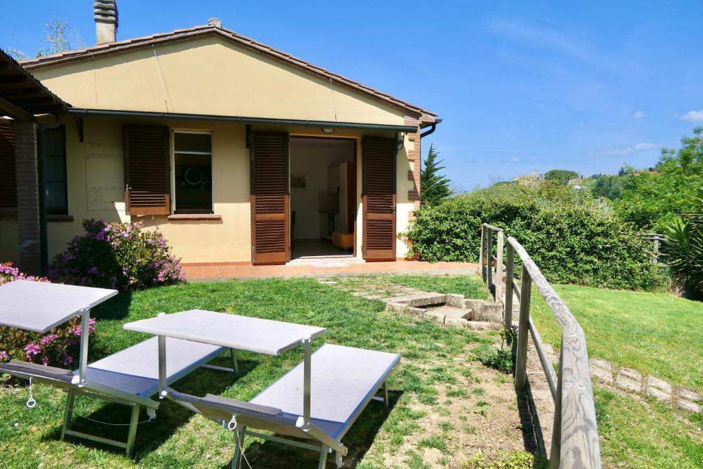 a house with two picnic tables in the yard at Chalet Elena in Montescudaio, ground floor with fenced garden in Montescudaio