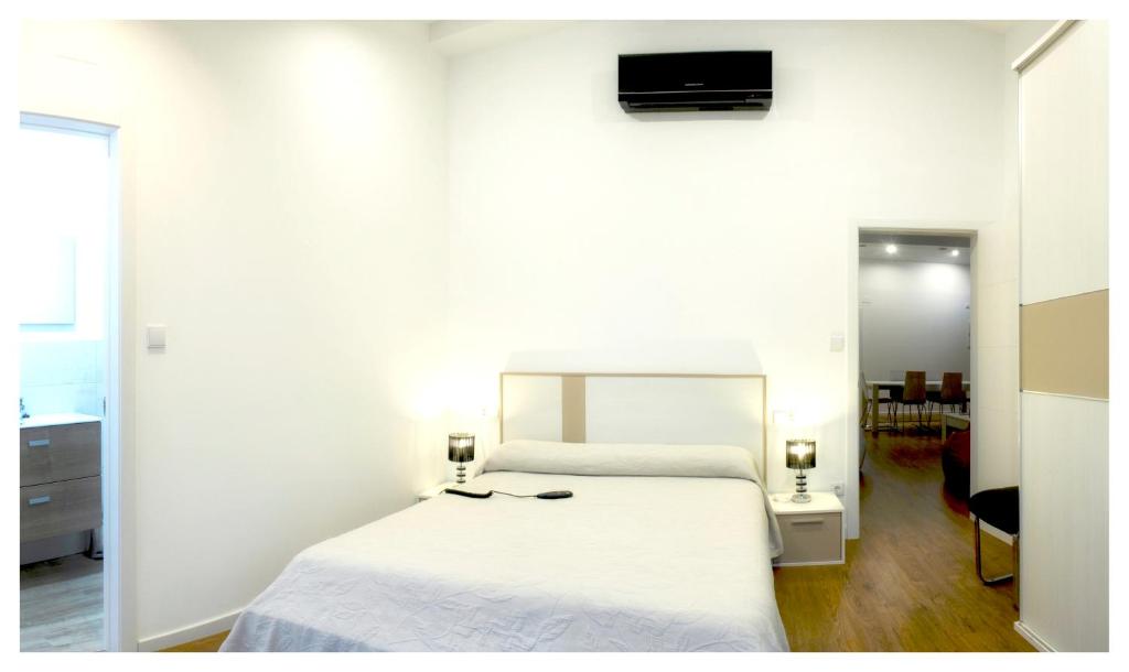 1 dormitorio con 1 cama blanca y TV en la pared en 3 bedrooms villa with private pool and wifi at Outes Tavilo 1 km away from the beach en Serantes