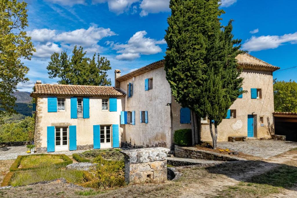 uma casa velha com persianas azuis e uma árvore em Villa de 6 chambres avec piscine privee jardin clos et wifi a Saignon em Saignon