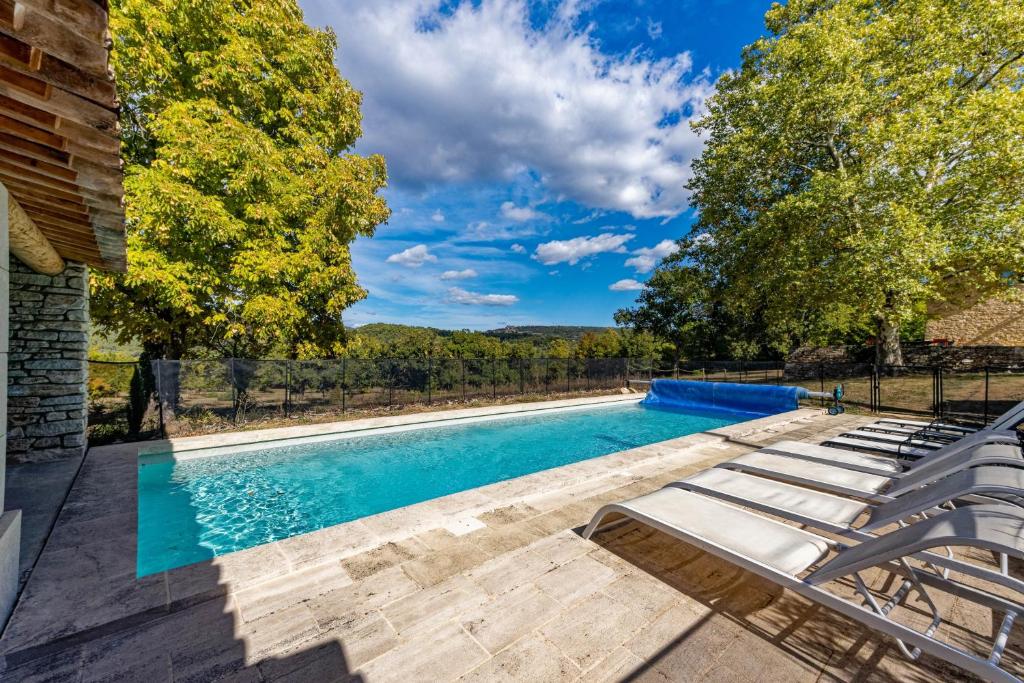 a swimming pool with lounge chairs next to a house at Villa de 6 chambres avec piscine privee jardin clos et wifi a Saignon in Saignon