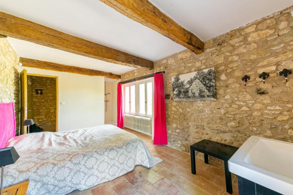 a bedroom with a bed and a stone wall at Villa de 6 chambres avec piscine privee jardin clos et wifi a Saignon in Saignon