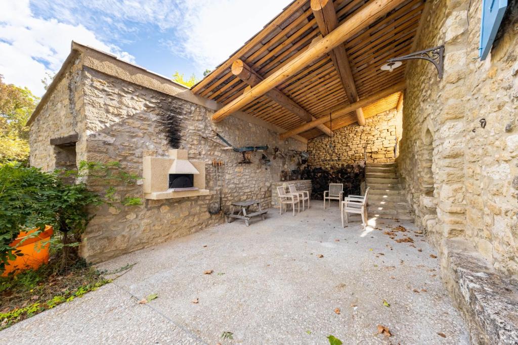an outdoor patio with a stone building with a wooden ceiling at Villa de 6 chambres avec piscine privee jardin clos et wifi a Saignon in Saignon