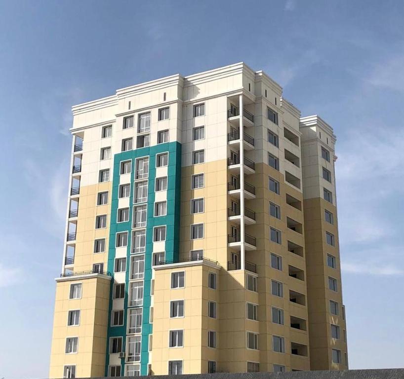 a tall apartment building with a blue sky in the background at Элитная новая квартира в Туркестане 2 in Türkistan