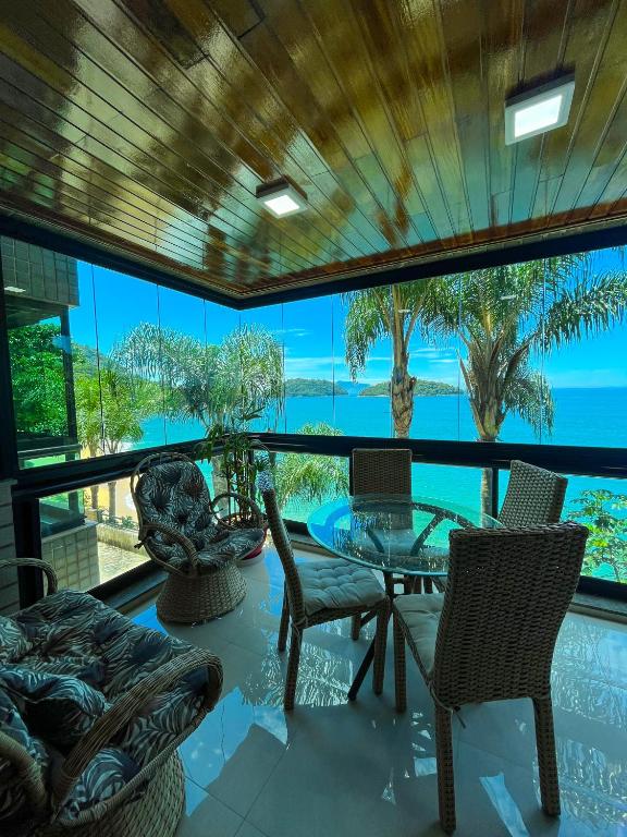 um quarto com uma mesa e cadeiras e vista para o oceano em Apartamento LUXO no Porto Real Resort ao lado da praia em Mangaratiba