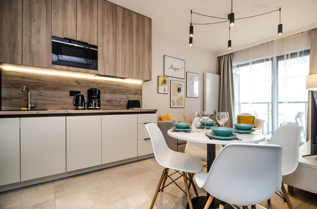 Apartamenty Shellter Rogowo - ALL DAY HOLIDAY في روغوفو: مطبخ وغرفة طعام مع طاولة وكراسي بيضاء