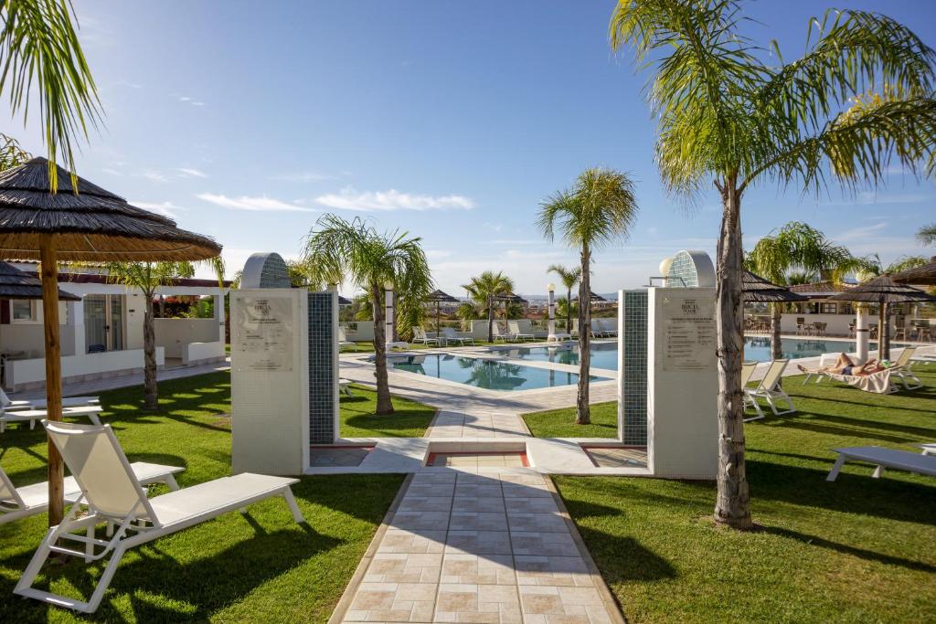 a resort with a swimming pool and palm trees at Hotel Rural Brícia Du Mar in Ferragudo