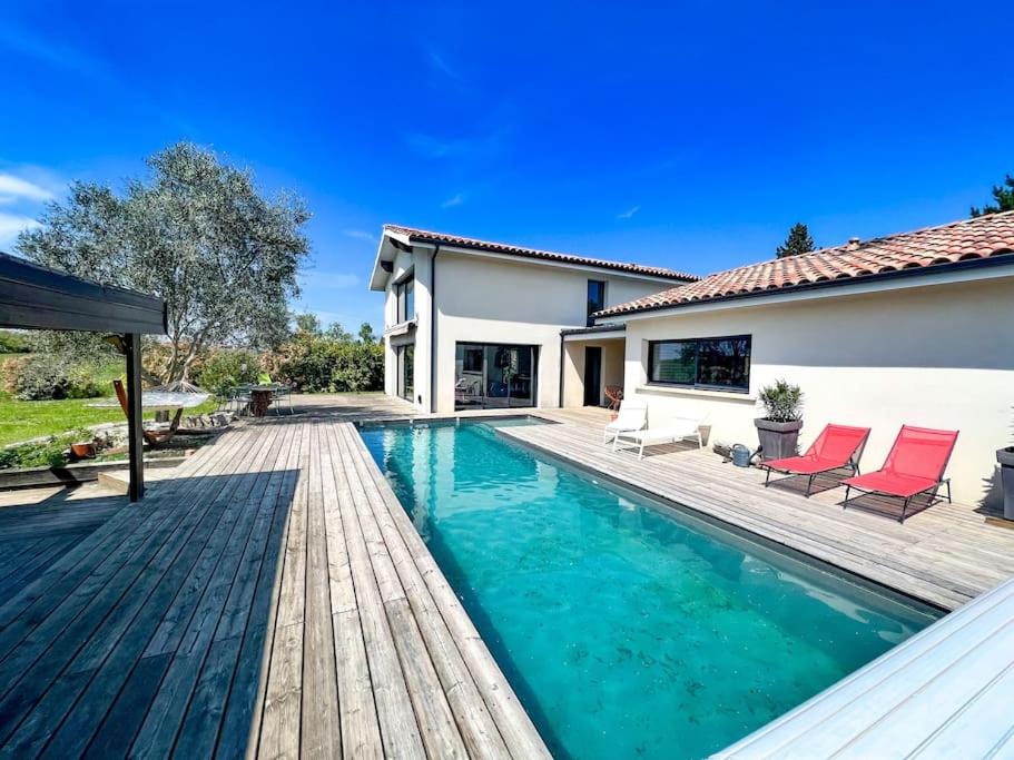 einem Pool mit Holzterrasse und einem Haus in der Unterkunft grande villa, piscine chauffée, proche Bordeaux in Lignan-de-Bordeaux