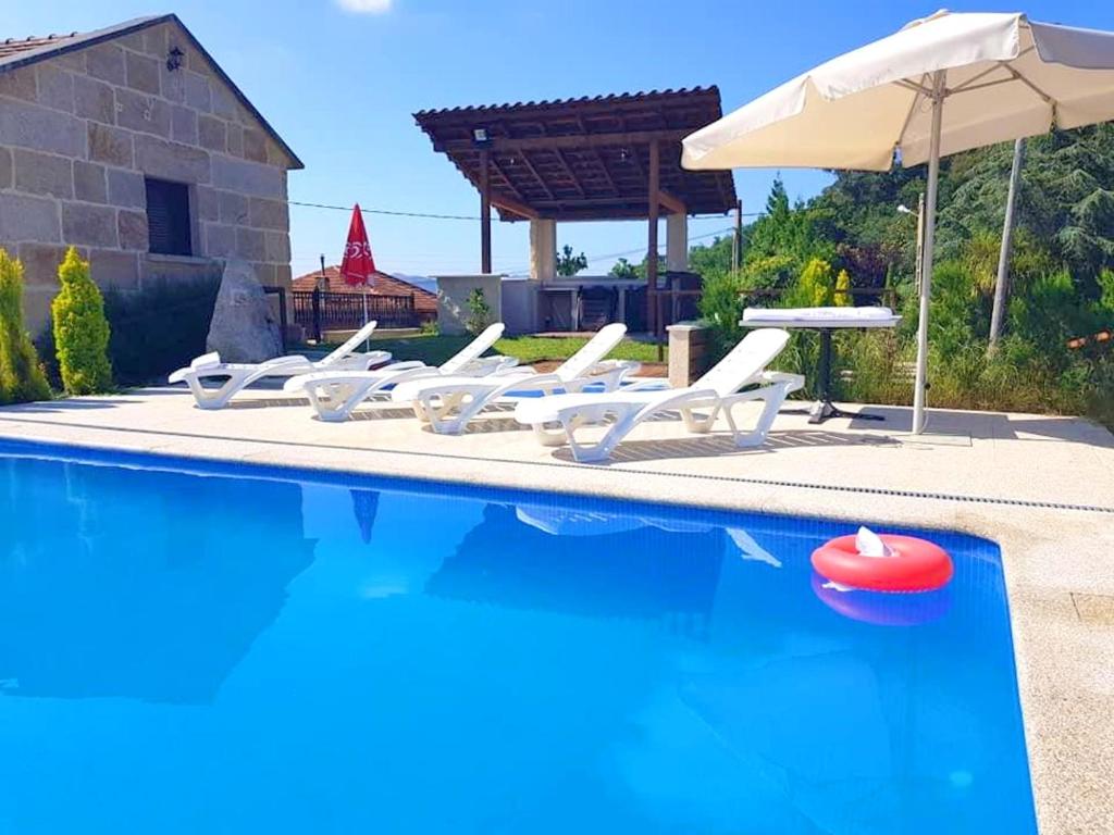 a group of chairs and an umbrella next to a swimming pool at 3 bedrooms house with private pool jacuzzi and enclosed garden at Pontevedra in Rífrío