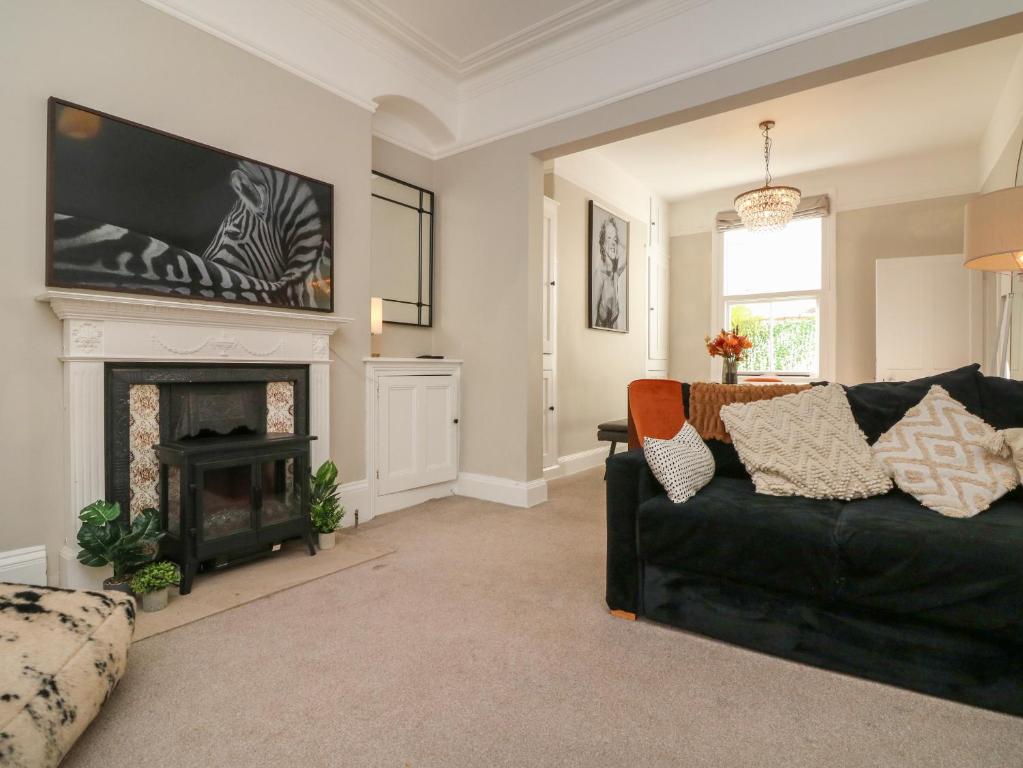 a living room with a black couch and a fireplace at Myrtle House in Ilfracombe